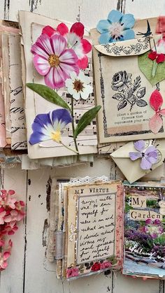 many different types of flowers are hanging on the wall with old papers attached to them