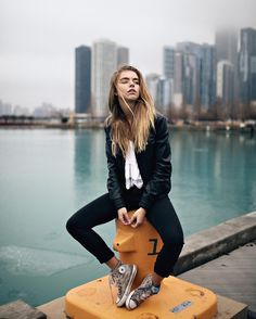 a woman sitting on top of a yellow object in front of a body of water