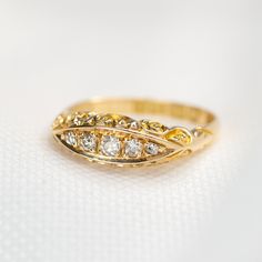 a yellow gold ring with three diamonds on the top and bottom, sitting on a white surface