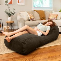 a woman laying on top of a bean bag chair in a living room next to a couch