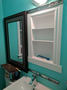 a bathroom with a sink, mirror and shelf above the bathtub is painted teal