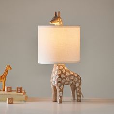 a giraffe lamp sitting on top of a table next to a stack of books