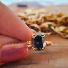 a hand holding an engagement ring with a black diamond in the middle and gold accents around it