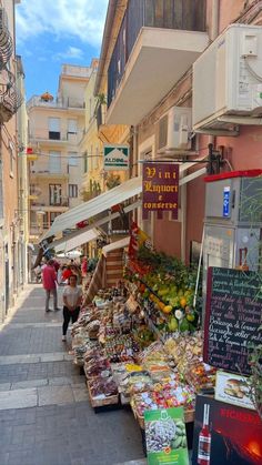 an outdoor market with lots of fruit and veggies on the tables in front of it