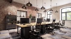 an office with brick walls and lots of desks in the center, along with two large windows