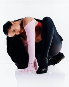 a woman in black tights and pink stockings posing for the camera with her hands on her knees