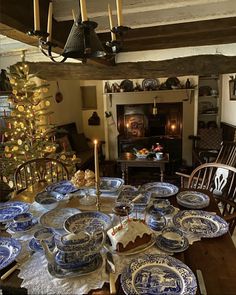 a dining room table with blue and white plates on it, next to a christmas tree