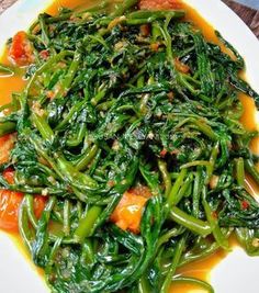 a white plate topped with green vegetables covered in sauce