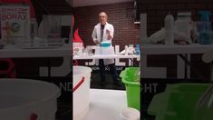 a man standing in front of a table filled with containers and cups on top of it