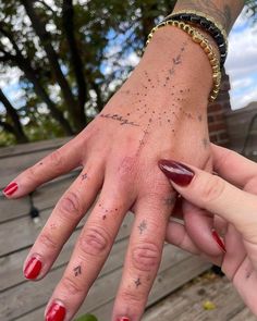 two hands with tattoos on them holding each other's fingers in front of a wooden deck