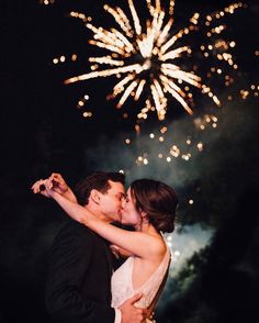 a bride and groom kissing in front of fireworks