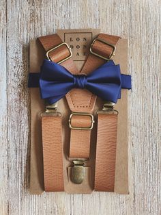 "Vintage Tan faux leather adjustable suspenders and navy satin bow tie. The perfect combination for your groomsmen, ring bearers, family photos or just because! * \"SET\" includes 1 pre tied bow tie and 1 suspender in selected size. * \"BOWTIE ONLY\" includes 1 bow tie in selected size. Does not include suspenders. Suspenders can be purchased individually using listings below: SKINNY 1/2\" WIDTH SUSPENDER ONLY LISTING LINK https://www.etsy.com/LondonJaeApparel/listing/584608801/brown-suspenders- Adjustable Dapper Belts And Suspenders For Party, Adjustable Bow Tie Back Belt For Wedding, Adjustable Wedding Belt With Bow Tie Back, Adjustable Bow Tie For Groom, Groomsmen Beach Wedding, Toddler Ring Bearer, Rustic Wedding Groomsmen, Brown Suspenders, Suspenders Wedding