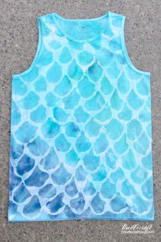 a tank top with blue and green watercolors on the front, sitting on concrete