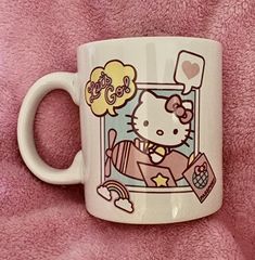 a hello kitty mug sitting on top of a pink blanket