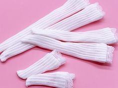 three white knitted gloves on a pink background