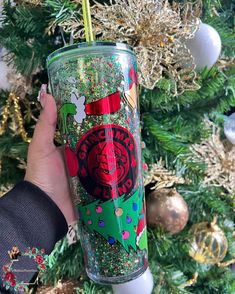 a person holding a starbucks cup in front of a christmas tree with ornaments on it