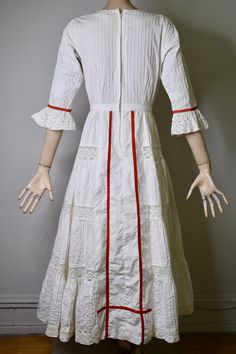 "This dress is so special. It is a vintage 60s/70s Mexican pin tucked white dress. The dress has a square neckline, that is trimmed with red ribbon and small lace ruffles, is fitted to the waist with a floral embroidered bodice that is also finished on the side with red ribbon, it has 3/4 sleeves with a flared lace cuff and red ribbon trim, The skirt is a long maxi skirt that is quite full, it has a front and back center panel with red ribbon running down the length, coming off the front panel i Fitted Broderie Anglaise Maxi Dress, Fitted Regency Style Dress In Vintage White, White Empire Waist Vintage Dress With Ruffles, White Empire Waist Prairie Dress, White Vintage Dress With Ruffles And Empire Waist, White Fitted Empire Waist Vintage Dress, White Victorian Dress With Lace Trim For Garden Party, White Fitted Vintage Dress With Empire Waist, White Lace Prairie Dress For Wedding