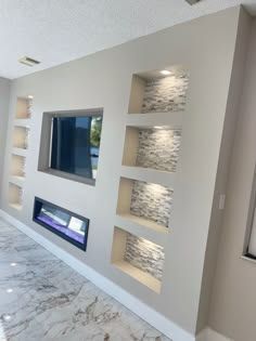 an empty living room with white walls and marble flooring in front of a flat screen tv mounted on the wall