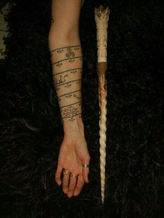 a person with a tattoo on their arm holding a stick