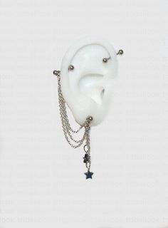 an ear with chains attached to it and a star charm hanging off the side of it