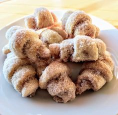 a white plate topped with donuts covered in powdered sugar