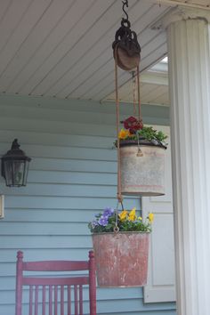 two buckets with flowers hanging from them on a porch next to a purple chair