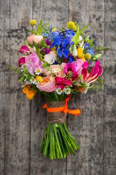 a bouquet of colorful flowers tied to a wooden wall