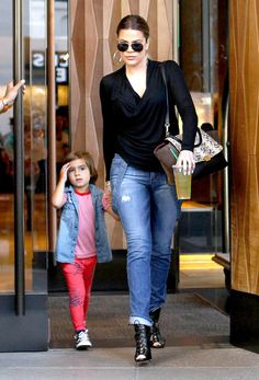 a woman and her daughter are walking out of a building with their hands in each other's pockets