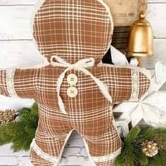 a brown teddy bear sitting on top of a wooden floor next to a bell and wreath