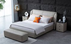 a modern bedroom with stone walls and flooring, including a bed that has an ottoman underneath it