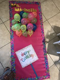 a birthday banner with balloons and a sign that says happy birthday on it in front of a tiled floor