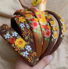 a hand is holding several different types of headbands with flowers on the sides