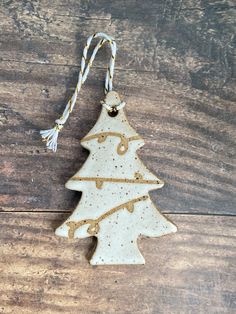 a ceramic ornament shaped like a christmas tree on a wooden table with string