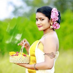 a beautiful woman holding a basket with flowers in it's hand and looking at the camera