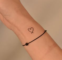 a woman's arm with a small heart tattoo on the left side of her wrist