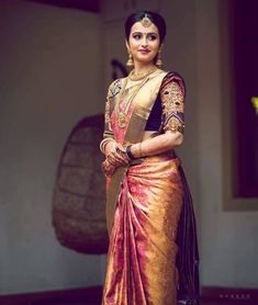 a woman in a gold and pink sari standing with her hands on her hips