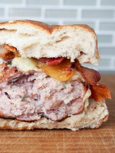 a close up of a sandwich with meat and cheese on a wooden table next to a brick wall