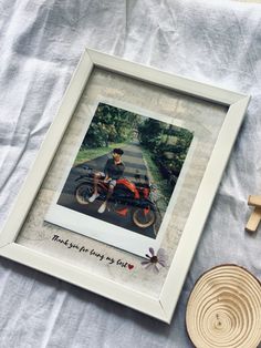 a photo frame with a man sitting on a motorcycle in front of it next to a wooden cross