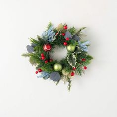 a christmas wreath on a white wall with ornaments and greenery around the wreath, top view from above