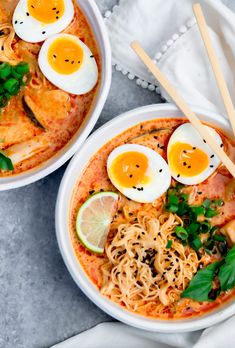 two bowls of ramen with hard boiled eggs on top and garnished with parsley