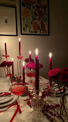 the table is set with candles, plates and red roses on it for a valentine's day dinner