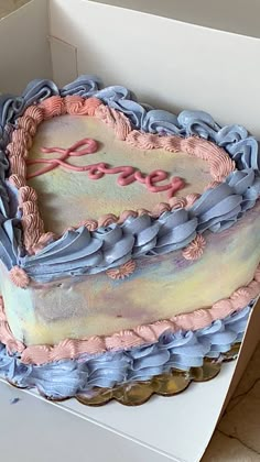 a heart shaped cake sitting on top of a white box with pink and blue frosting