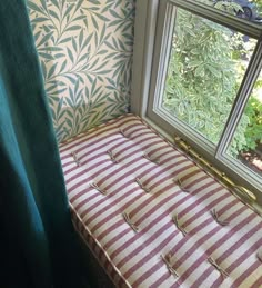 a bench sitting in front of a window next to a green curtain