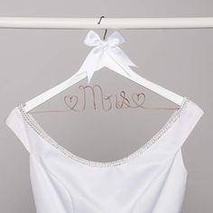 a white wedding dress hanging on a hanger with the word mrse spelled in cursive font