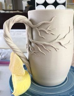 a white mug sitting on top of a blue plate next to a yellow piece of cloth