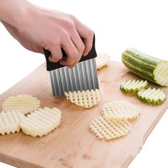 a person using a grater to cut up some food on a cutting board next to cucumbers