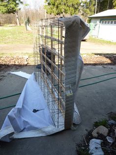 a large bird cage sitting on top of a tarp in the middle of a yard