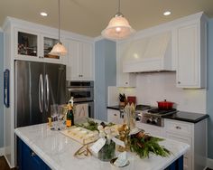 a kitchen with white cabinets and marble counter tops is decorated in blue and white colors