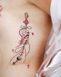 a woman's breast with an artistic tattoo design on her left side ribcage