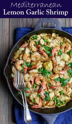 a skillet filled with shrimp and vegetables on top of a blue towel next to a fork